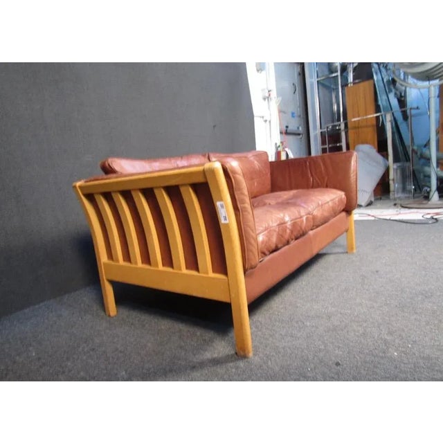 Combining leather upholstery with wooden frames, this vintage couch offers comfortable seating through a stylish Mid-...