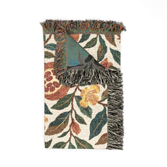 This Arts and Crafts-style pomegranate woven throw blanket features winding leafy branches, rust-colored fruit, and blue...
