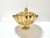 A dramatic large-scale Hollywood Regency brass pedestal bowl featuring a scalloped rim, ornate scroll handles, and a...