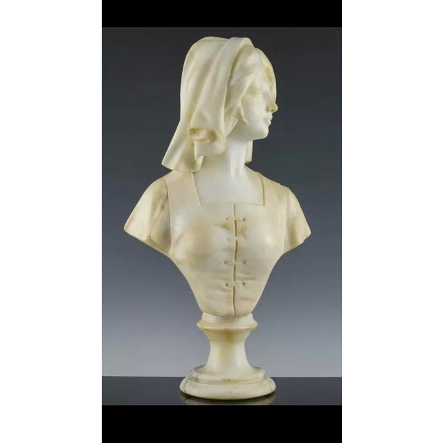 Beautiful hand-carved alabaster bust of a young maiden. Great detailing to the headscarf and blouse, the bust is attached...