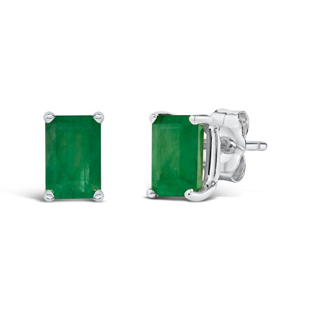Immerse yourself in the timeless elegance of these stud earrings, each boasting a lustrous 6x4mm emerald-cut green...