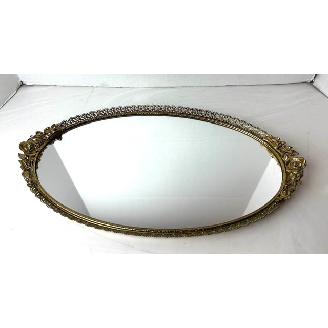 Hollywood Regency goldtone dresser mirror . Rose motif, pierced floral border rail . Measures 16.5” x 9.5” x 1.5. Felt...