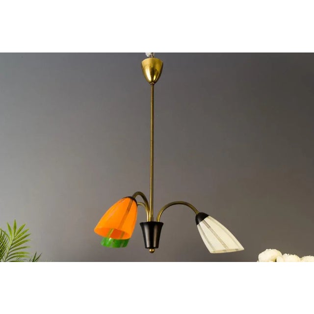 Midcentury Belgian pendant light with three brass arms, each with a different color glass shade - green, white, and orange...