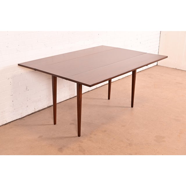 A sleek and stylish Mid-Century Modern solid walnut drop-leaf harvest dining table By Jack Cartwright for Founders...