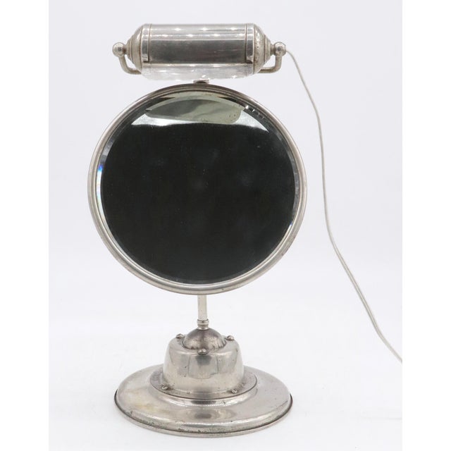 Early 20th century tabletop mirror glass with a heavy duty nickel base and built in lighting fixture. Slight tarnishing...