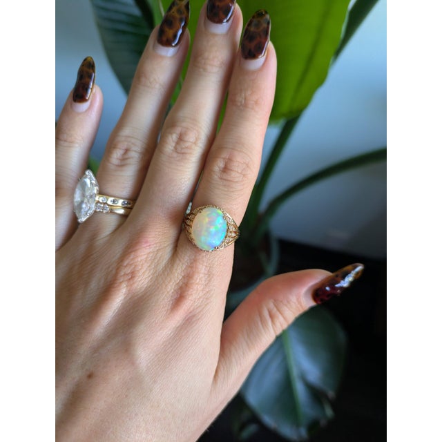 A 5.6-carat ethiopian opal cabochon sits at the centre of this solid 14K yellow gold ring, framed by fifty-six earth-mined...
