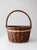 A vintage wicker gathering basket in a rich mix of natural tones, with a softly time-worn patina that adds depth and...