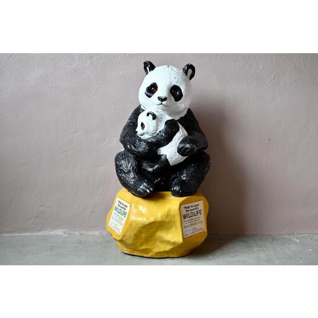 A giant panda and its cub nestled together, this large animal cast is a donation box for the World Wildlife Foundation....