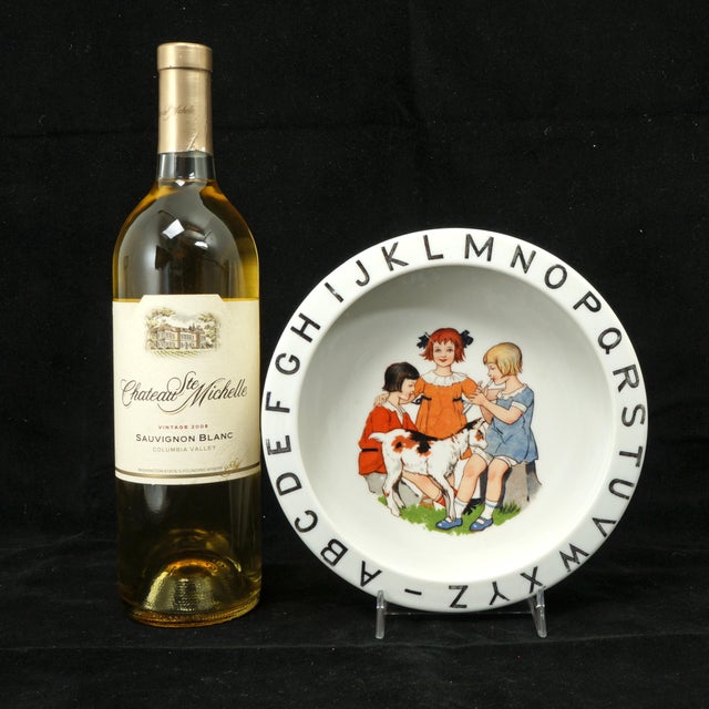 A vintage German porcelain child's bowl featuring a colorful transferware image of three girls playing with a goat,...