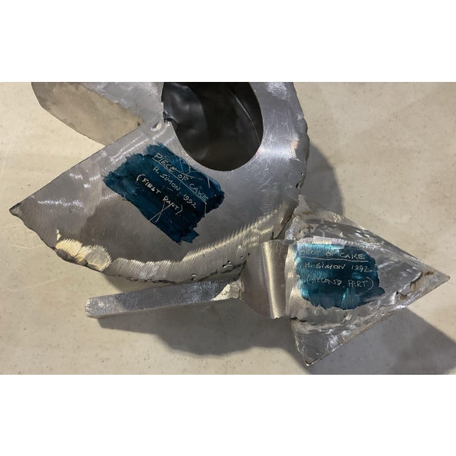 A whimsical aluminum sculpture titled "Piece of Cake," by Pennsylvania sculptor Herbert Simon, dated 1992. Two elements: a...