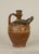 An earthenware ewer with an animal head spout with an open mouth and tooled fur texture. Consistent with rural pottery...