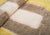 A soft golden-yellow field frames a single sculptural taupe motif — an open, keyhole-like arch outlined in richly textured...