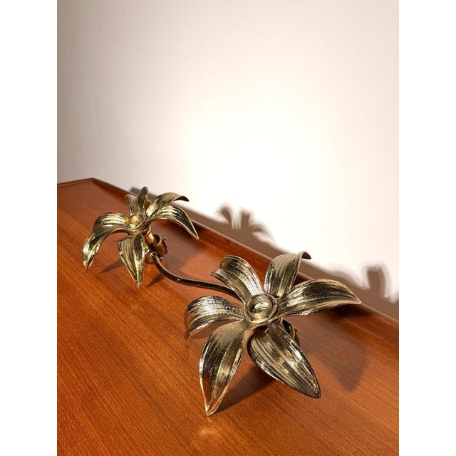 Elegant vintage wall lamp featuring two sculptural floral light points connected by a flowing curved arm. Crafted in...