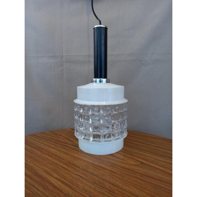 Ceiling lamp with smooth white pressed glass lampshade at the top and bottom and embossed with symmetrical motifs on the...