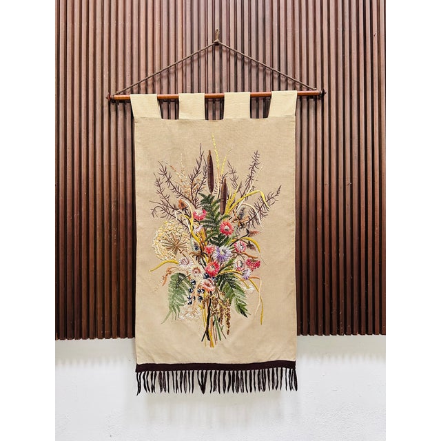 A finely crafted wall hanging from the 1950s, hand-embroidered with silk and wool thread on a warm-toned linen blend. The...