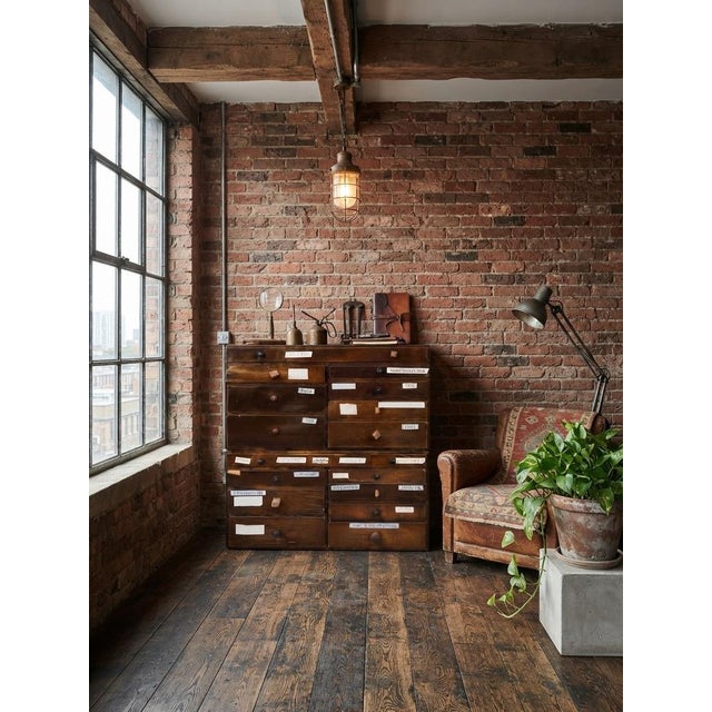 A unique and authentic Hungarian vintage wooden tool cabinet featuring multiple stacked drawers equipped with original...