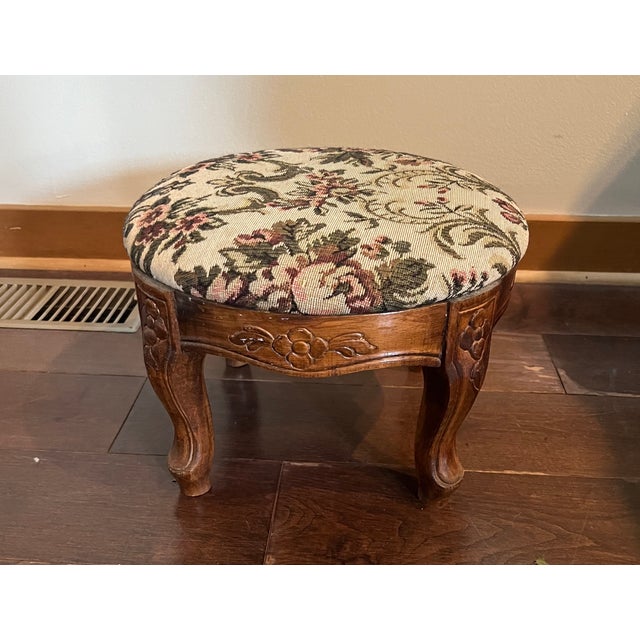Charming vintage footstool featuring beautifully carved solid wood detailing and elegant cabriole-style legs. The...