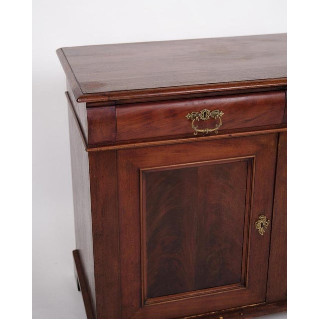 Low antique sideboard from the 1880s, made of hand-polished mahogany. The sideboard is furnished with fixed shelves and...