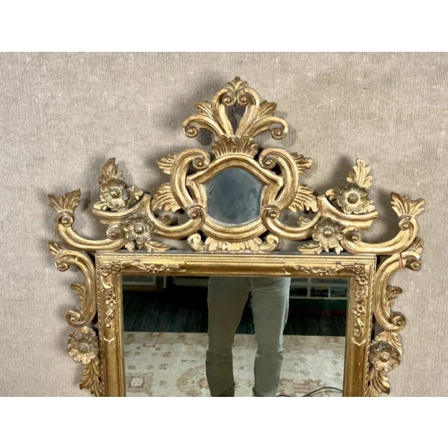 An early 20th century carved and gilt wood wall mirror with an ornately carved crest and “S. Cavallo Inc.” marking on...