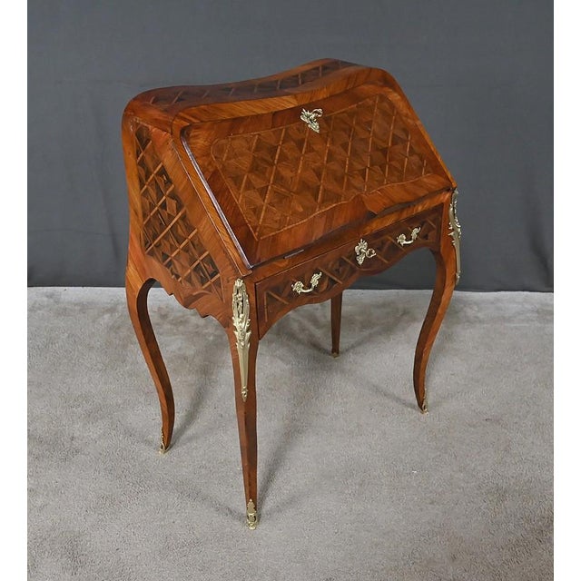 This small marquetry lady's desk, crafted in the Louis XV style, boasts a delicately curved silhouette. Its surfaces are...