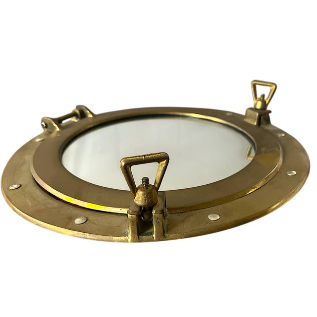 Classic maritime style meets timeless craftsmanship in this solid brass porthole mirror. Measuring 11.5” in diameter and...
