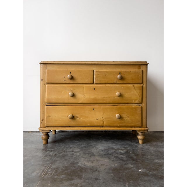 An antique Victorian English pine chest of drawers. Two short drawers over two long drawers with wood knobs, on turned...