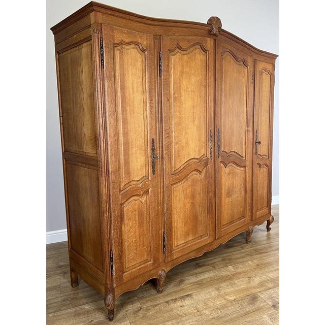 An elegant Vintage French Louis wardrobe in oak, featuring four panelled doors, a gently shaped top, decorative central...