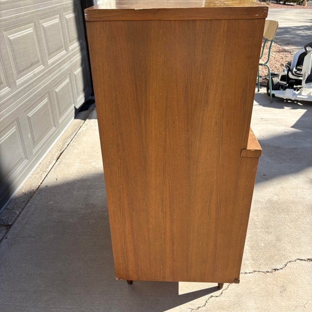 Vintage mid-century modern highboy dresser has five spacious drawers with walnut wood veneer. Piece features unique...