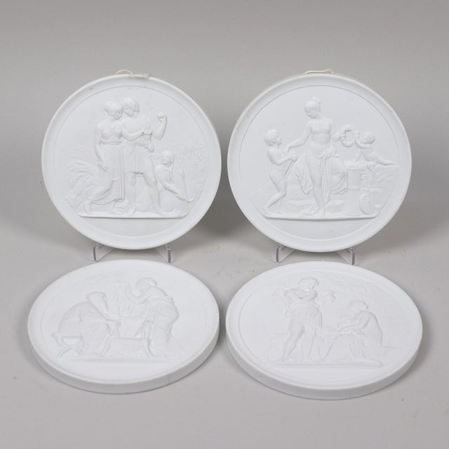 A beautiful set of four Royal Copenhagen biscuit porcelain wall relief plaques featuring elegant neoclassical scenes...