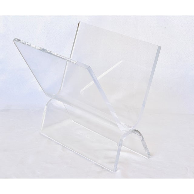 A bent Lucite magazine holder. Two pieces of thick heavy Lucite are joined to create a simple functional form. In the...