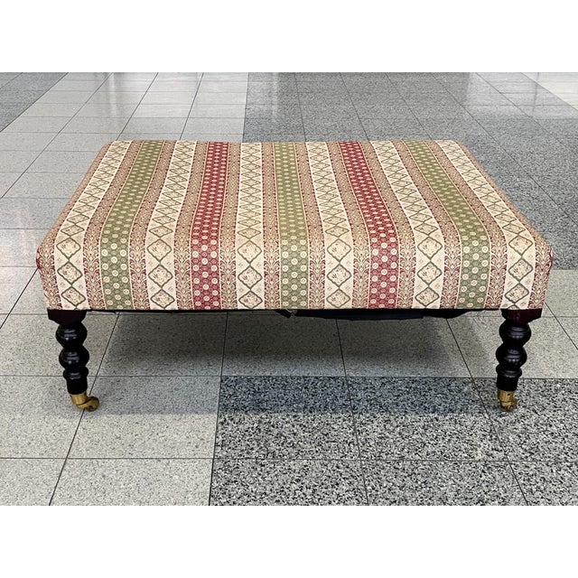 A classic George Smith ottoman upholstered in a colorful, floral-and-stripe patterned weave. The turned wooden legs...