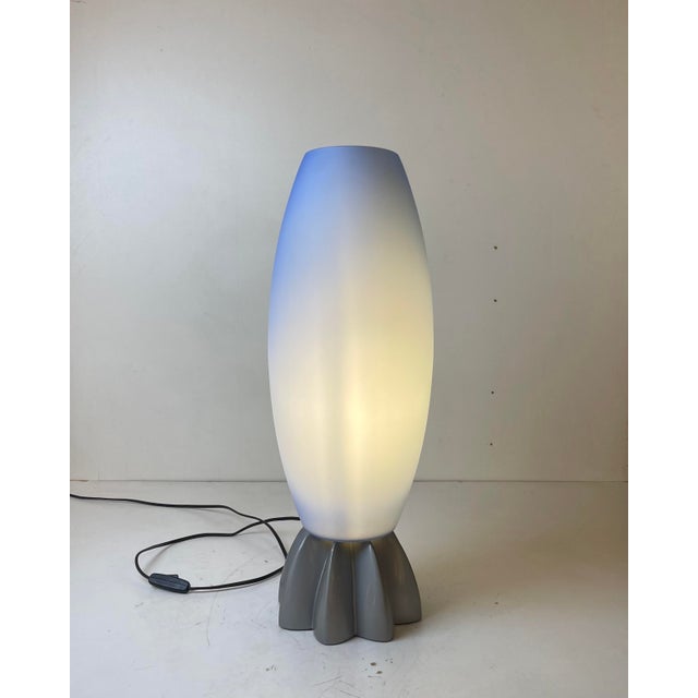 Astonishing table lamp with an industrial fluted aluminum base under an elongated, oval-shaped shade of blown, frosted...