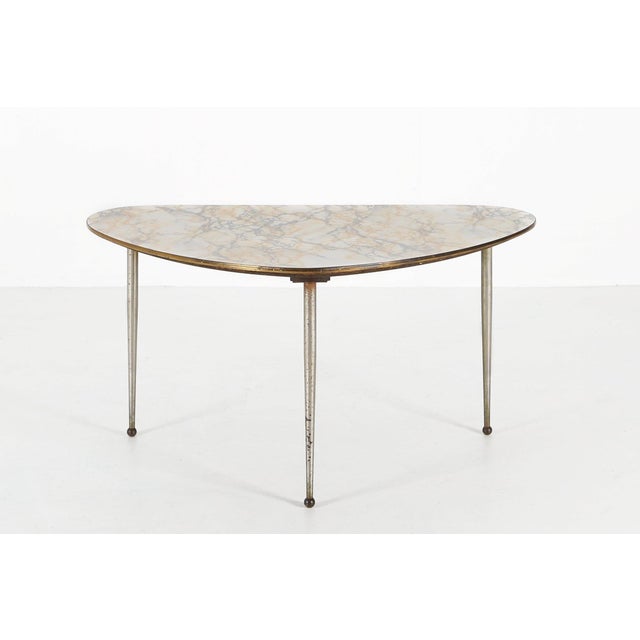 A sculptural Belgian mid‑century coffee table from the 1960s, distinguished by its organic, triangular form and elegant...