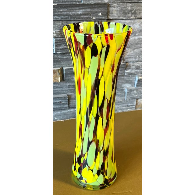 This tall, slender art glass vase was hand-blown from crystal-clear glass. Its pristine surface a canvas for nature's...