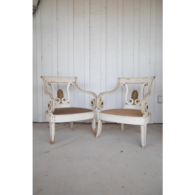 This wooden cream color chair with a cane seat and scroll arms from Sweden in 1870 would likely be a beautiful and well-...
