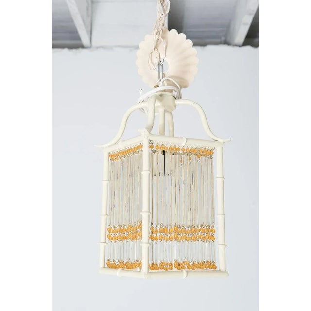 This is a pair of small Pagoda style faux bamboo white painted metal lanterns. Each Chinoiserie lantern has gold color...