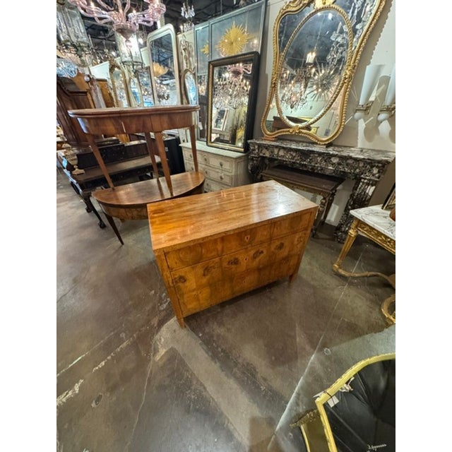 The product is a 19th-century German Biedermeier walnut commode. This commode features intricate craftsmanship and design...