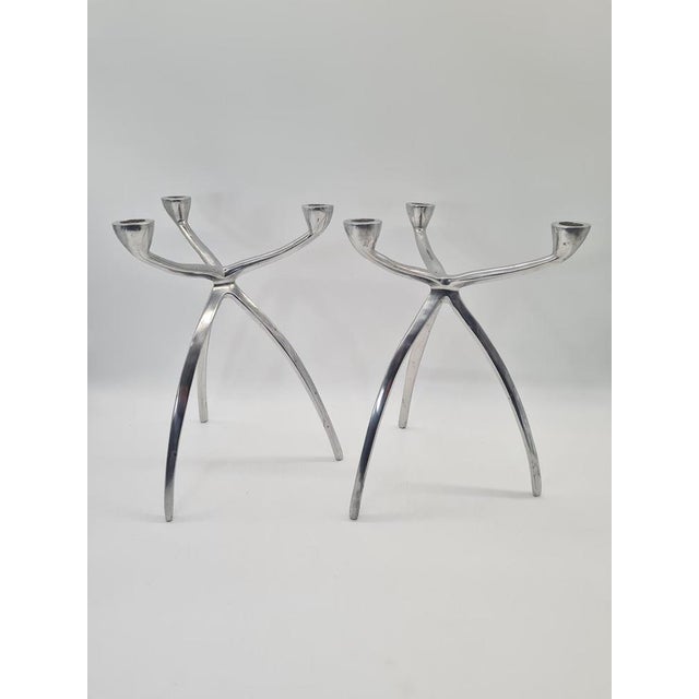 A sculptural pair of candlesticks made of polished aluminum in a distinctive modernist form reminiscent of an organic...
