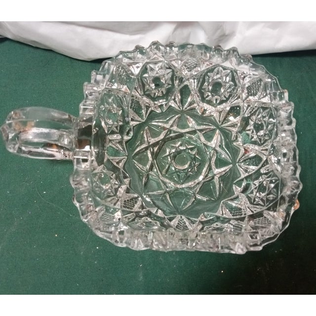 This is an Early American Pattern Glass Nappy Dish made in 1890 by the Fostoria company. It's squarish with one handle and...