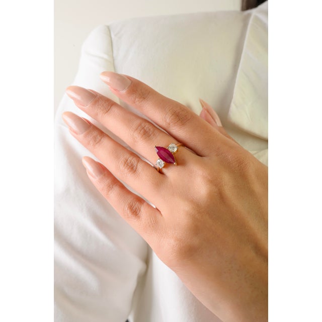 This elegant three-stone ring features 1 marquise cut natural ruby totaling 1.29 carats, set in rich 14k yellow gold. The...