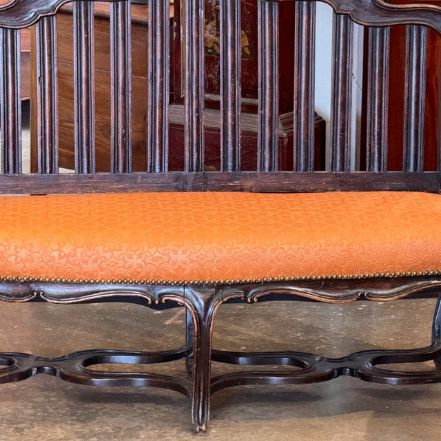 Italian walnut settee with shaped crest rail above a spindle back, scrolled arms, and an upholstered seat with nailhead...