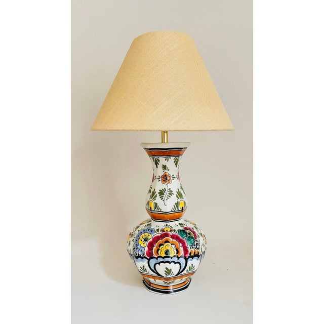A pair of 20th century delft vase lamps, in a classic garlic neck shape. Each lamp is decorated on an off white ground...