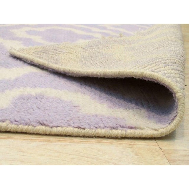 This contemporary wool rug features a hand knotted pile construction in a distinct purple color palette. The primary hues...