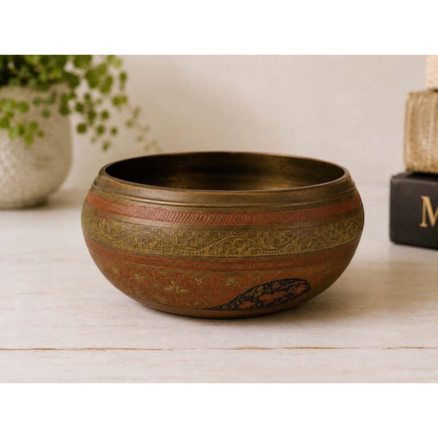A richly detailed vintage Indian brass bowl featuring hand-etched floral and foliate motifs highlighted with red and black...