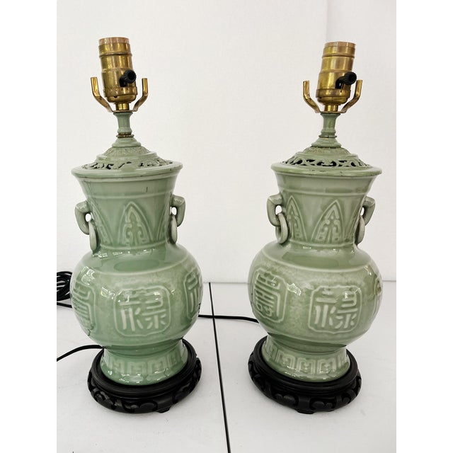 Crafted in the 1940s, these table lamps have ceramic bodies, brass hardware, and ebonized wood bases. The ceramic bodies...