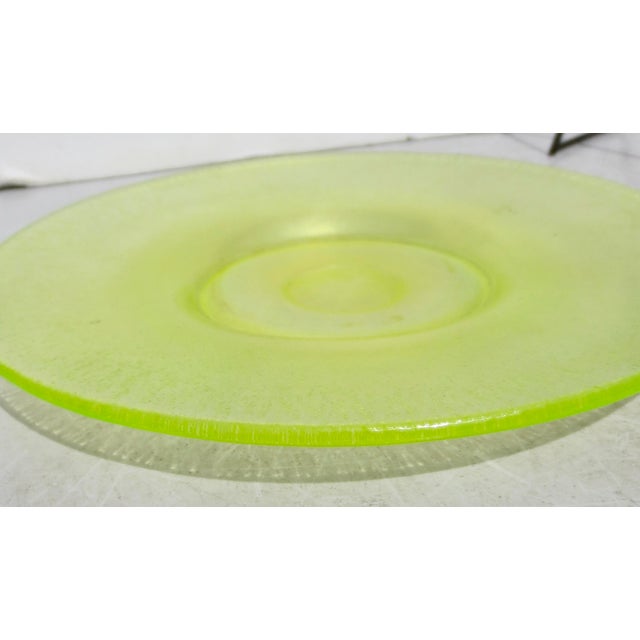 Hand blown round plate having a vaseline uranium green tone with iridescent vitriol. Pontil mark seen to bottom. Measures...