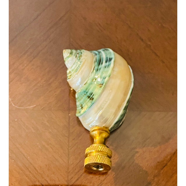 Serpentine blue polished mother of pearl turbo sea shells on a brass base as lamp finial.