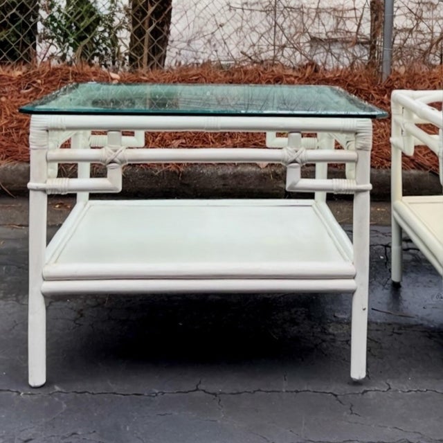 This is a pair of white Ficks Reed Chinese Chippendale style rattan side tables with glass tops. The bottom shelf is wood....