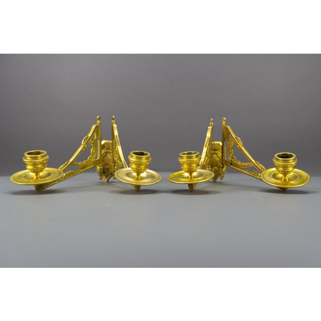 A pair of Art Deco ornate piano or wall lights, candleholders by Leon Pinet. Each sconce has two arms, each for one...