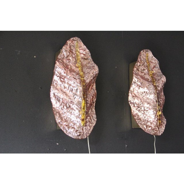Here is a beautiful pair of wall sconces made of pearlescent pink Murano glass, shaped like leaves or feathers, mounted on...